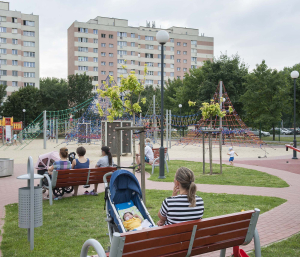 23 July 2015 – Katarzyna sits with her doll, while her children play in a park, in Warsaw, Poland. Whenever Katarzyna takes her children out, the doll usually comes too.