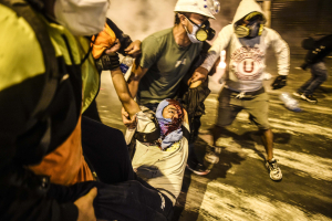 14 November 2020 – Demonstrators help an injured fellow protester, during clashes with riot police following a protest against the government of interim president Manuel Merino in Lima, Peru.