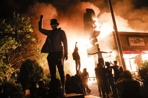 29 May 2020 – Protesters raise their fists in defiance outside a burning fast-food restaurant near the precinct station of the officers who arrested Floyd, in Minneapolis, Minnesota, USA.