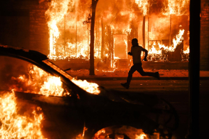 30 May 2020 – A protester runs past burning cars and buildings on Chicago Avenue, Saturday, in St Paul, Minnesota, USA. Some 75 fires were reported around the city on 29 and 30 May.