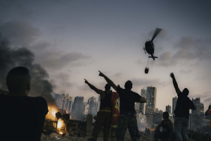 4 August 2020 – Men direct a helicopter to drop water on the site of a powerful explosion in the port area of Beirut, Lebanon.